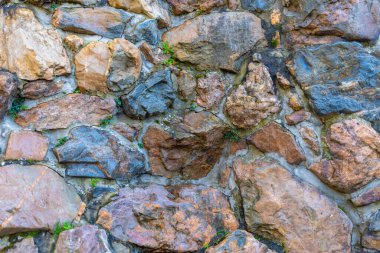 Çok renkli kayalık yüzey, sıkı sıkıya sarılmış düzensiz şekilli taşlarla, yeşil bitki örtüsü kayaların yarıklarının arasından kırılarak, arazinin organik yapısını oluşturur.,