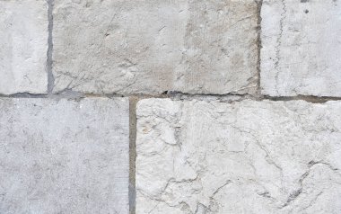 Eski, yıpranmış duvar çeşitli dokulara sahip büyük doğal gri taşlarla kaplı. Taşlar, harç ve dış duvarın mimari detaylarıyla dolu görünür dikişlerle döşenmiş.