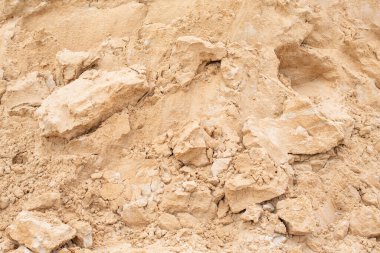 Açık kahverengi kum ve kir yığını çeşitli boyutlarda parçalarla kaba tanecikli bir dokuyu ortaya çıkarıyor. Doğal bir yapı malzemesi ya da toprak arkaplan olarak kullanışlı.
