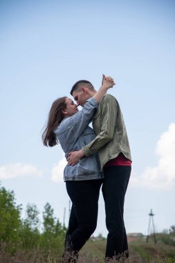 Young man and woman embracing each other, looking into eyes with love and intimacy, expressing a deep emotional connection and relationship outdoors under a clear sky