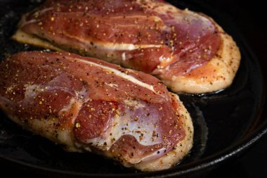 İki ördek göğsü, tuzlu ve biberli bir tavada kızartılır.