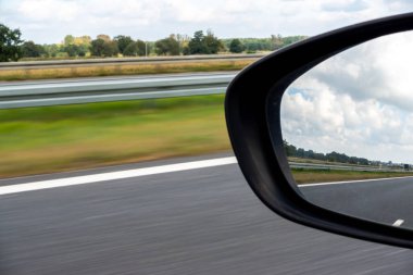 Yolcu vagonunun dikiz aynasından bak. Fotoğraf araba sürerken çekildi. Arka planda bulanık yol. Fotoğraf doğal ışıklandırma koşullarında çekildi.