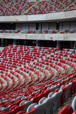 Futbol stadyumunda boş beyaz ve kırmızı sandalyeler. Yaklaşan bir spor ya da kültürel etkinliğin beklentisi.