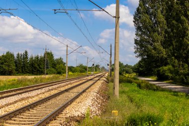 Tracks of an electric railway line on a hot summer day. Perspective shot from human eye level.
