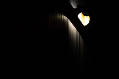 Karanlık bir odada, ruh hali aydınlatmasının yakın çekimi. Siyah duvarlar, oyuklu bir yapıya sahip panellerle tamamlanmış.