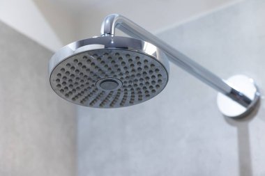 Duş başlığı duş tepsisinin duvarına sabitlendi. Yukarıdan banyoya püskürtülen bir duş.