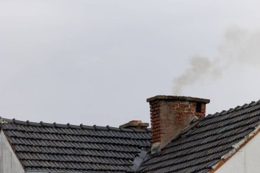 Toxic smoke flying from the chimney of a detached house. Combating smog from burning coal and waste