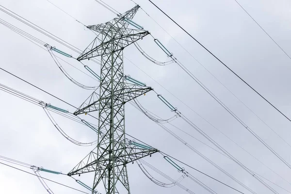 The silhouette of a high-voltage pylon against a completely cloudy sky. Development of high-voltage transmission networks