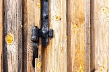 Eski, siyah menteşe parçaları bir demirci tarafından yapılmış. Eski bir barakanın eski ahşap kapısına monte edilmiş cihazlar.