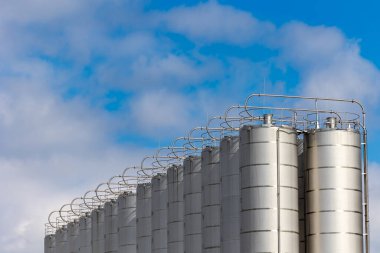 Mavi gökyüzüne karşı paslanmaz çelik silolar. Plastik ve toplu tahıl depolama depoları.