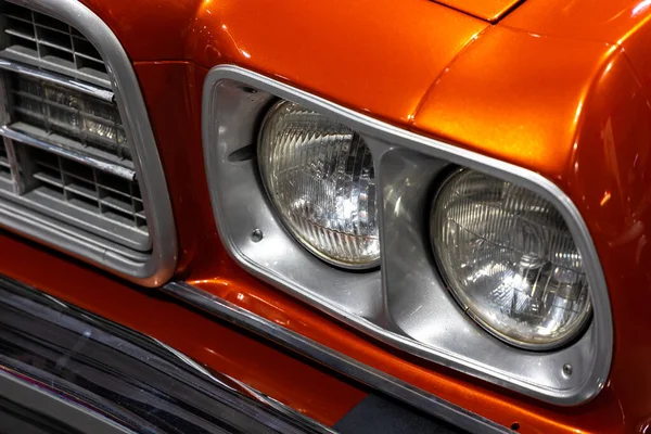 オレンジのアメリカンクラシックカーのラウンドヘッドライトのクローズアップ 歴史的な車両のクロムの詳細上の天然のパティーン — ストック写真