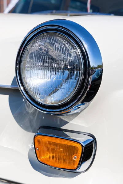 白いクラシックカーのラウンドヘッドライトとオレンジのターン信号のクローズアップ 歴史的な車両の美しく復元されたクロムの詳細 — ストック写真