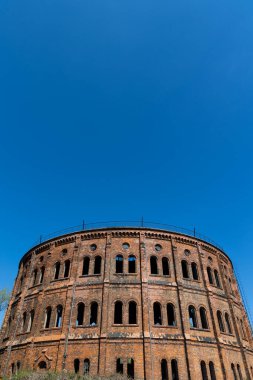 Kırmızı tuğladan yapılmış terk edilmiş sanayi binası. 19. yüzyıl endüstriyel mimarisinin bir örneği. Fotoğraf güneşli bir günde çekildi. Mavi gökyüzüne karşı duran nesne.