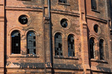 Kırmızı tuğladan yapılmış terk edilmiş sanayi binası. 19. yüzyıl endüstriyel mimarisinin bir örneği. Fotoğraf güneşli bir günde çekildi. Mavi gökyüzüne karşı duran nesne.