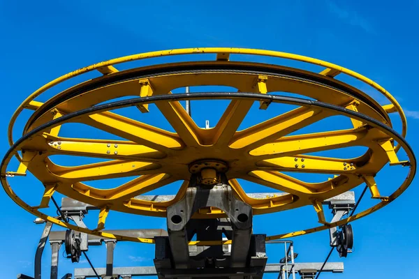 stock image Details of the construction of a mountain chairlift. View of a large drive wheel against a blue sky