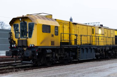 Demiryolu kenarında duran rayları öğütmek için kullanılan sarı bir teknik tren. Demiryolu hatlarını iyi durumda tutmak için ekipman