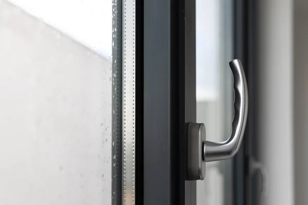 Stock image Tilt and turn window handle in a large window in a public building. The window is made of plastic, visible silicone seals.