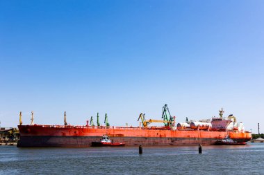 LNG tankeri limanda manevra yapıyor. Gemiyi liman kanallarında döndürmek için römorkör / satıcı kullanıyor. Güneşli bir günde çekilmiş..
