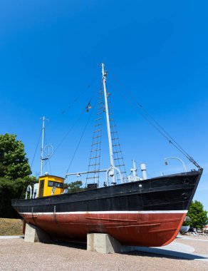Tarihi bir balıkçı teknesi sudan çıkarıldı ve müzenin rıhtımında sergilendi. Güneşli bir günde, mavi gökyüzüne karşı çekilen bir gemi.