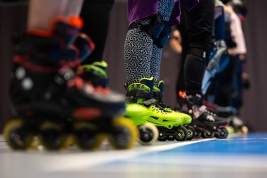 Spor salonunda artistik patinaj eğitimi alan insanların patenlerine yakın çekim. Fotoğraf spor salonunun yapay ışıklandırmasıyla çekildi..