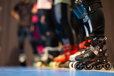 Spor salonunda artistik patinaj eğitimi alan insanların patenlerine yakın çekim. Fotoğraf spor salonunun yapay ışıklandırmasıyla çekildi..