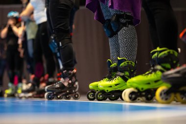 Spor salonunda artistik patinaj eğitimi alan insanların patenlerine yakın çekim. Fotoğraf spor salonunun yapay ışıklandırmasıyla çekildi..
