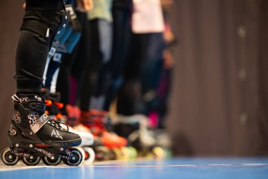 Spor salonunda artistik patinaj eğitimi alan insanların patenlerine yakın çekim. Fotoğraf spor salonunun yapay ışıklandırmasıyla çekildi..