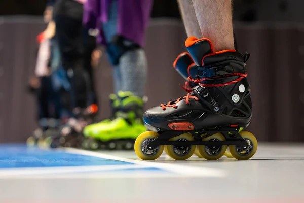 Spor salonunda artistik patinaj eğitimi alan insanların patenlerine yakın çekim. Fotoğraf spor salonunun yapay ışıklandırmasıyla çekildi..