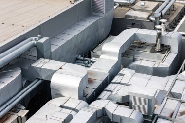 Binanın çatısında havalandırma ve havalandırma kanalları var. Fotoğraf doğal, yumuşak bir ışıkla çekilmiş. Yukarıdan görüntüle.