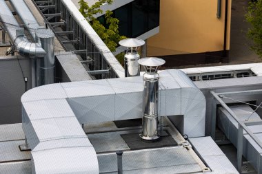 Binanın çatısında havalandırma ve havalandırma kanalları var. Fotoğraf doğal, yumuşak bir ışıkla çekilmiş. Yukarıdan görüntüle.