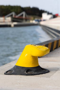 Beton iskelede sarı demirleme kancası. Rıhtıma demirlemiş teknelerin güvenliği. Fotoğraf güneşli bir günde çekildi.