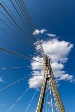 Halat köprüsünün beton direğindeki ipleri onarıyorum. Mavi gökyüzüne karşı köprü yapılarının görüntüsü