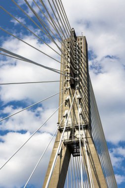Halat köprüsünün beton direğindeki ipleri onarıyorum. Mavi gökyüzüne karşı köprü yapılarının görüntüsü