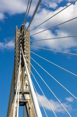 Halat köprüsünün beton direğindeki ipleri onarıyorum. Mavi gökyüzüne karşı köprü yapılarının görüntüsü