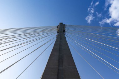 Halat köprüsünün beton direğindeki ipleri onarıyorum. Mavi gökyüzüne karşı köprü yapılarının görüntüsü