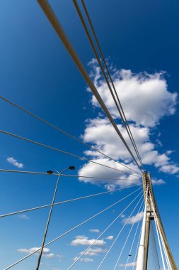 Halat köprüsünün beton direğindeki ipleri onarıyorum. Mavi gökyüzüne karşı köprü yapılarının görüntüsü