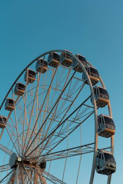 Mavi gökyüzünün arka planında dönme dolap. Bir sürü kapalı kamarası olan çelik inşaatın detayları. Öğleden sonra çekildi..  