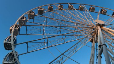 Mavi gökyüzünün arka planında dönme dolap. Bir sürü kapalı kamarası olan çelik inşaatın detayları. Öğleden sonra çekildi..  