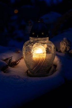 Geceleri mumlar karla kaplı mezarlarda yanıyor. Bir kış akşamı mezarlık manzarası