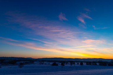 Güneş karla kaplı tarlaların üzerinden doğuyor. Ufukta altın bir parıltı. Kış gününün soğuk ve soğuk sabahları 
