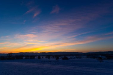Güneş karla kaplı tarlaların üzerinden doğuyor. Ufukta altın bir parıltı. Kış gününün soğuk ve soğuk sabahları 