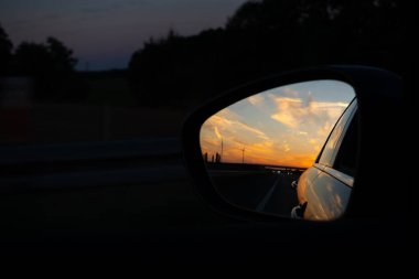 Bir arabanın dikiz aynasından bak. Arabanın içinden görüntüyü al. Otobanda akşam gezintisi.