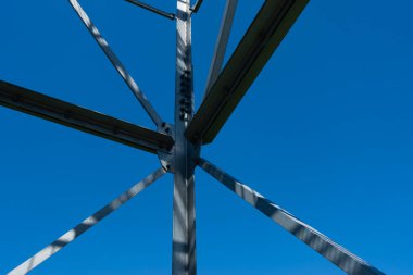 Gözlem kulesinin çelik elementlerinin sürgülü bağlantıları. Mavi gökyüzü arka planına karşı galvanize çeliğin yapı detayları.