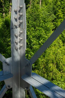 Gözlem kulesinin çelik elementlerinin sürgülü bağlantıları. Yeşil bir arka planda galvanizli çeliğin yapı detayları