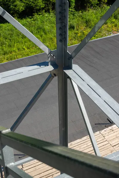 stock image Bolted connections of steel elements of the observation tower. Construction details of galvanized steel against a grey asphalt road surphace