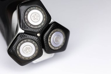 Beyaz arka planda sakallı elektrikli tıraş makinesi. Kesici bıçaklara yakın çekim. Fotoğraf yapay ışıkla çekilmiş. Tıraş makinesinin gözle görülür detaylarıyla.