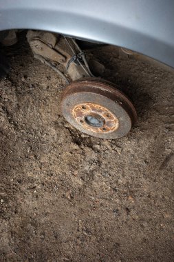 Terk edilmiş bir yolcu vagonunun paslı merkezi. Gri bir arabanın görünür tekerlek kemerleri. Fotoğraf doğal ışıklandırma koşullarında çekildi.