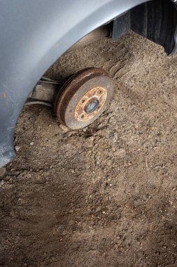 Terk edilmiş bir yolcu vagonunun paslı merkezi. Gri bir arabanın görünür tekerlek kemerleri. Fotoğraf doğal ışıklandırma koşullarında çekildi.