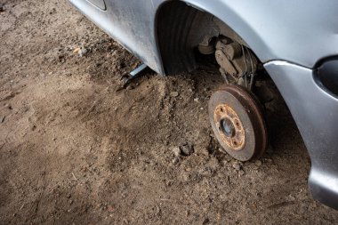Terk edilmiş bir yolcu vagonunun paslı merkezi. Gri bir arabanın görünür tekerlek kemerleri. Fotoğraf doğal ışıklandırma koşullarında çekildi.