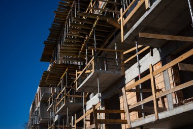 Yeni yapılmış kırmızı tuğlalı bir apartmanın çelik iskelesi. Fotoğraf, mavi gökyüzü ile güneşli bir günde çekildi.. 